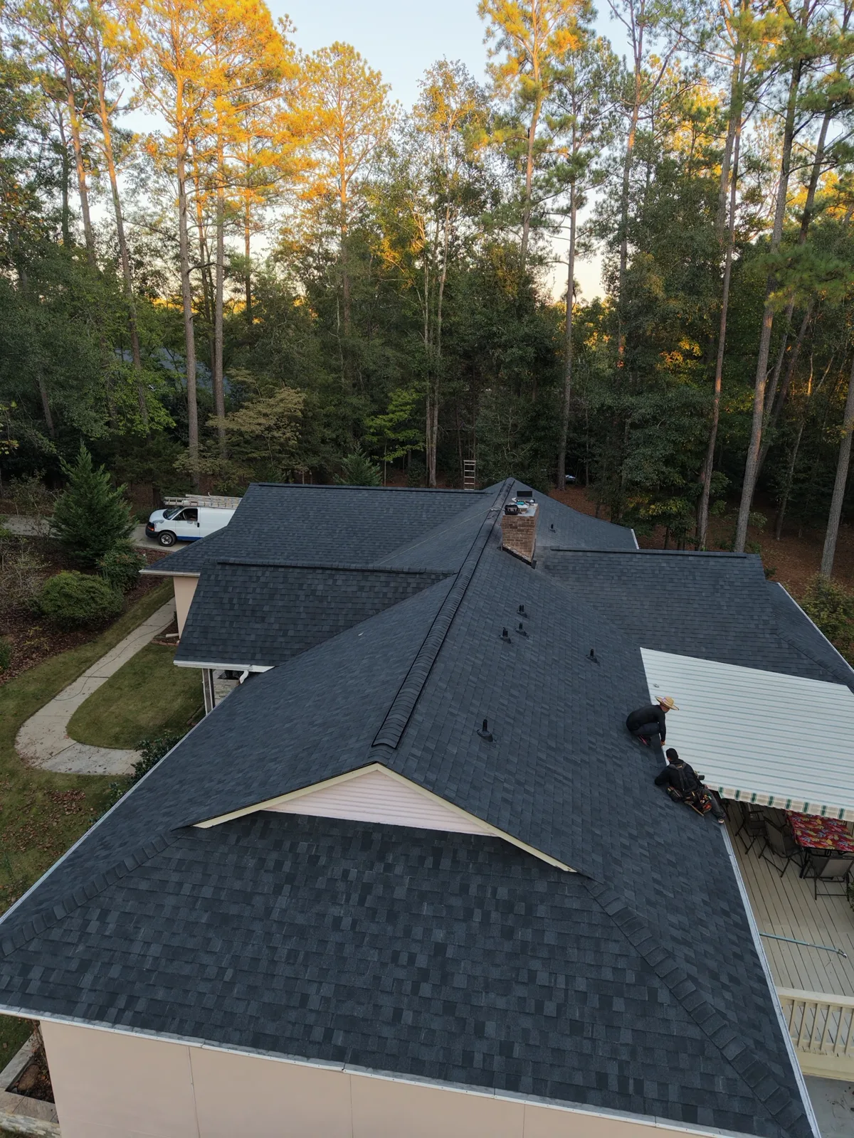 Bluebird Roofing crew at work on a new dark shingle roof, seen from above