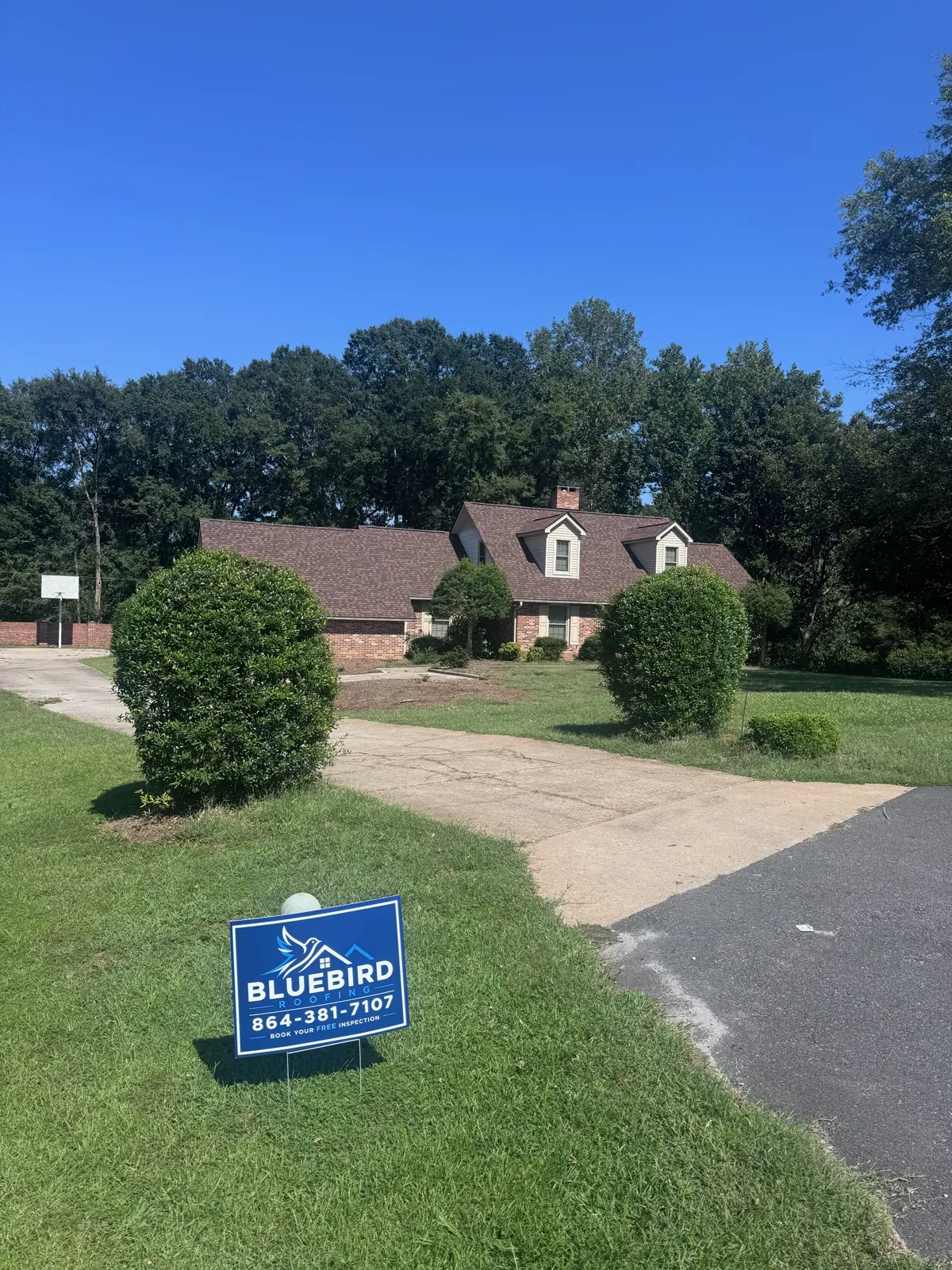Home with a new roof and a Bluebird Roofing yard sign out front
